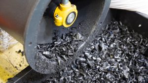 Resina plástica saindo do moedor na linha de reciclagem