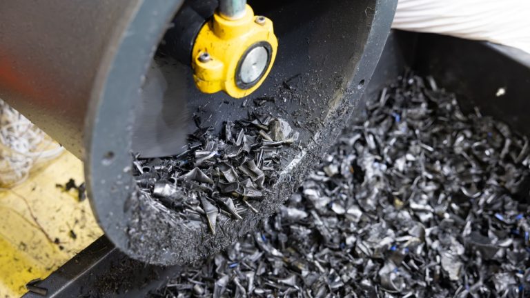 Resina plástica saindo do moedor na linha de reciclagem