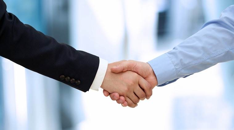 Image of a firm handshake  between two colleagues in office.
