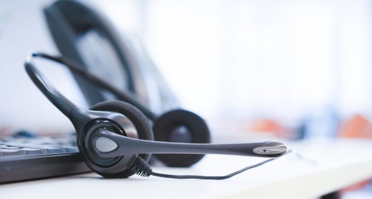 close up headset of call center and VOIP telephone for communication technology on office desk in monitoring room for network operation job concept