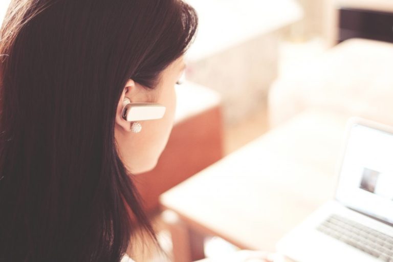 woman-wearing-earpiece-using-white-laptop-computer-210647