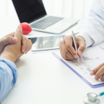 Esta imagem é um close-up focado na interação e documentação durante uma consulta médica ou reunião de aconselhamento de saúde.
