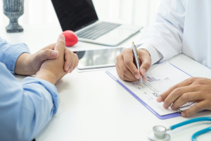 Esta imagem é um close-up focado na interação e documentação durante uma consulta médica ou reunião de aconselhamento de saúde.