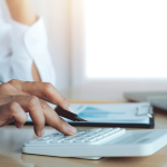 Um close-up das mãos de uma pessoa em um ambiente de escritório calculando ROI