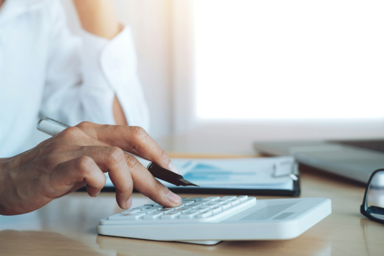 Um close-up das mãos de uma pessoa em um ambiente de escritório calculando ROI