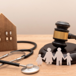 Estetoscópio, martelo de juiz, casa de madeira e família de papel sobre mesa.