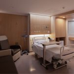 Quarto hospitalar moderno, com cama ao centro, mesa de apoio, suporte de soro, poltronas para acompanhante e bancada com pia. Ambiente claro, organizado e acolhedor, com acabamento em madeira clara.